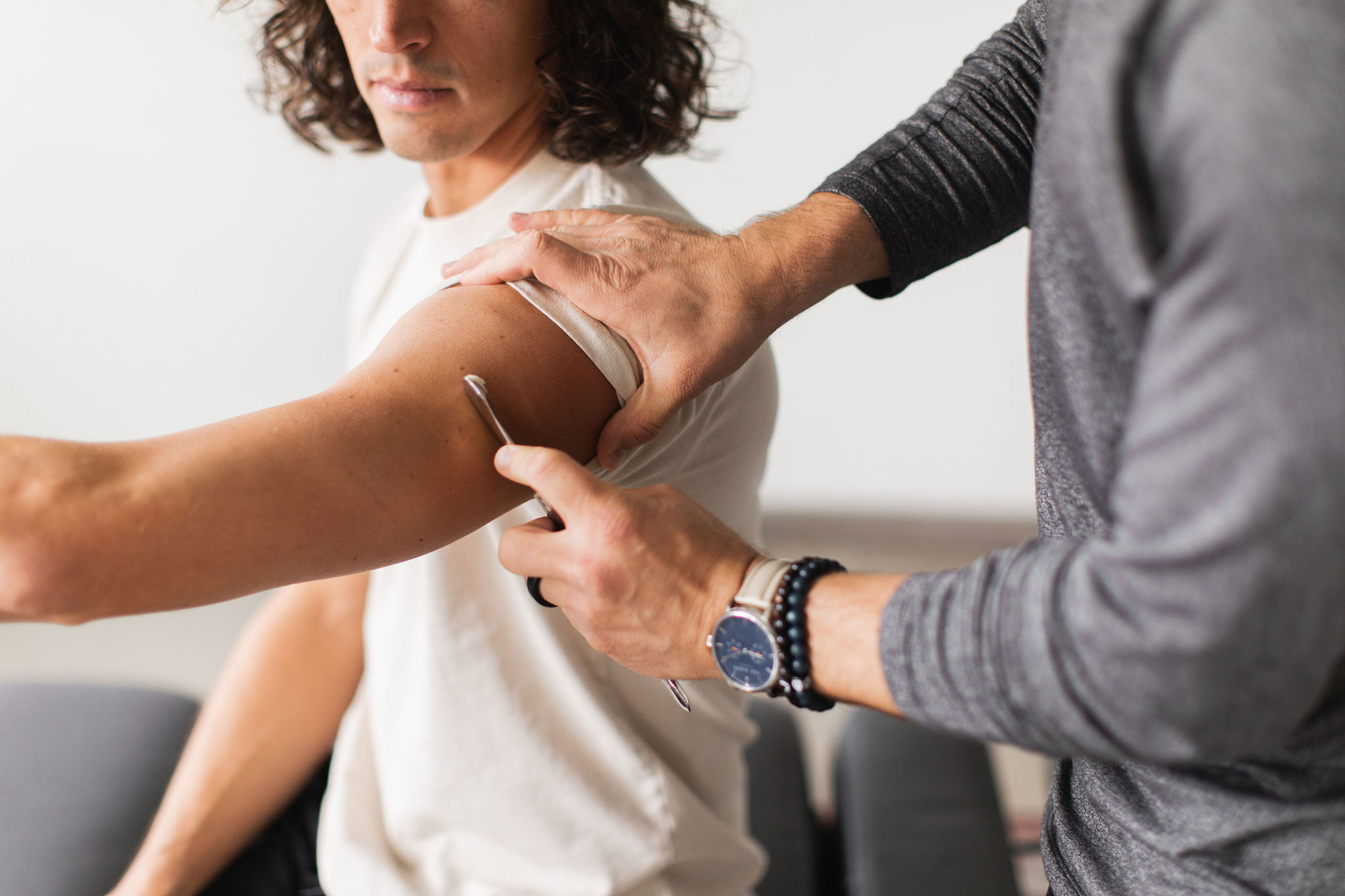 Chiropractic care performing soft tissue therapy using an instrument-assisted technique on a patient's arm to alleviate tension and improve mobility.